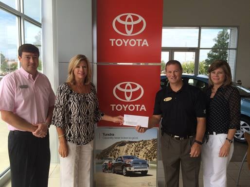 group of people standing in front of a Toyota logo banner